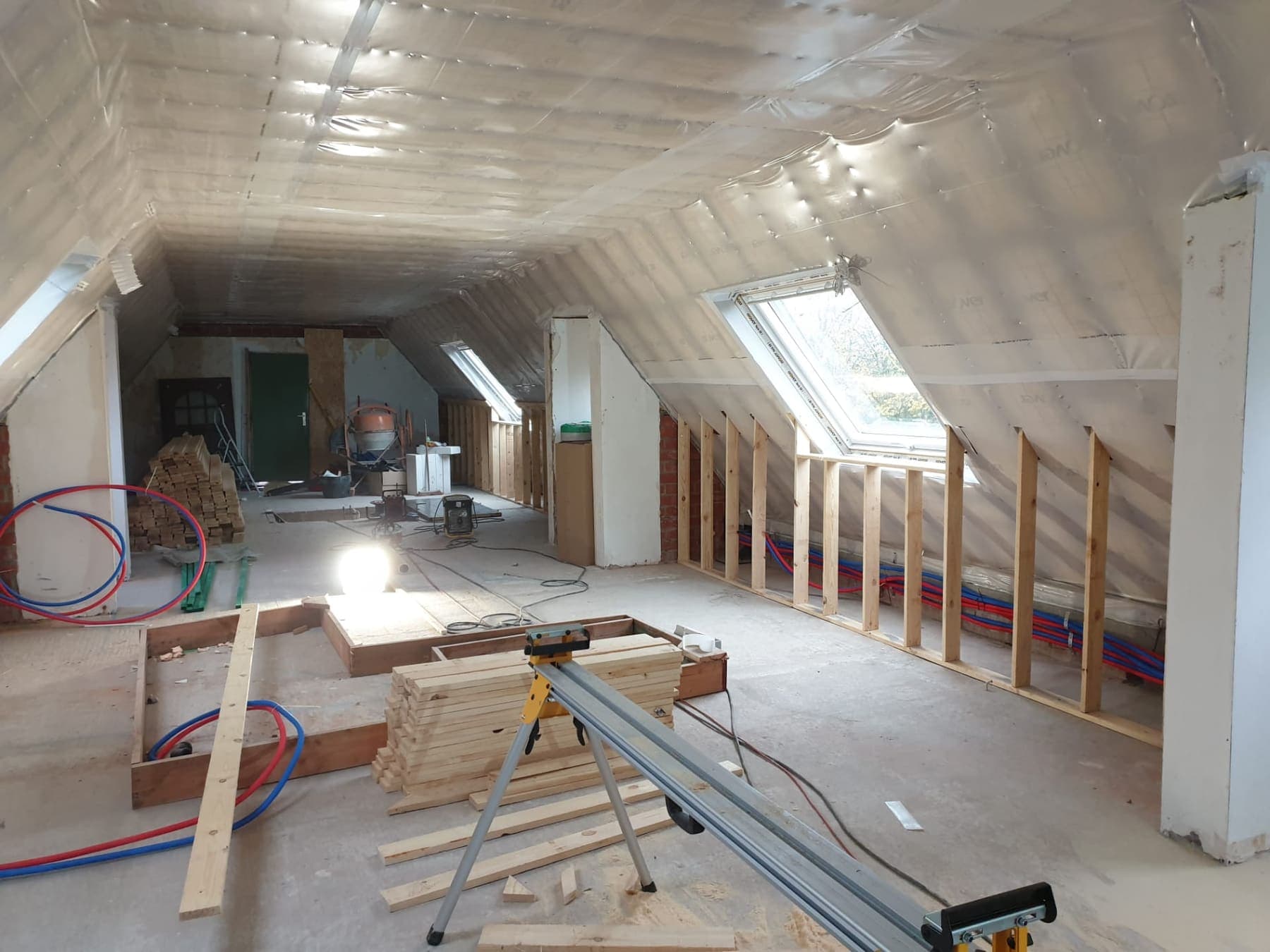 Zolderverdieping in verbouwing met een geïsoleerde kap, nieuwe houten wandframes en aangelegd leidingwerk.